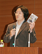著書を手に講演する門田さん