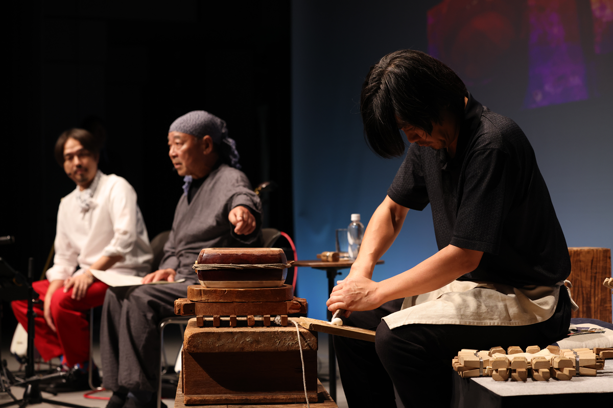 ステージ上で実演された津軽三味線の作業工程を解説する加藤さん（中央）と小山さん（左）