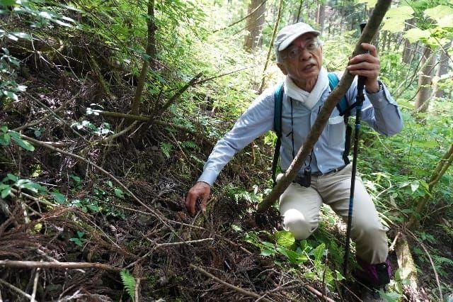 （奥多摩の「天然水の森」で土壌の変化を説明する山田さん）